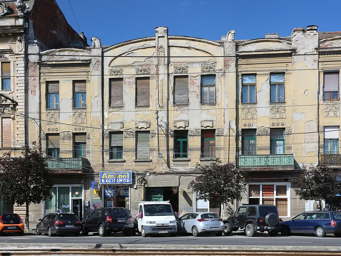 A faded but ornate Art Nouveau facade on Bulevardul General Ioan Dragalina in Iosefin, Timisoara, with a currency exchange sign on the ground floor