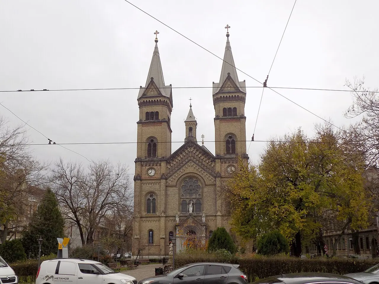 The twin neo-Romanesque towers of the Millennium Church in the Fabric district of Timisoara, seen across a square lined with bare winter trees